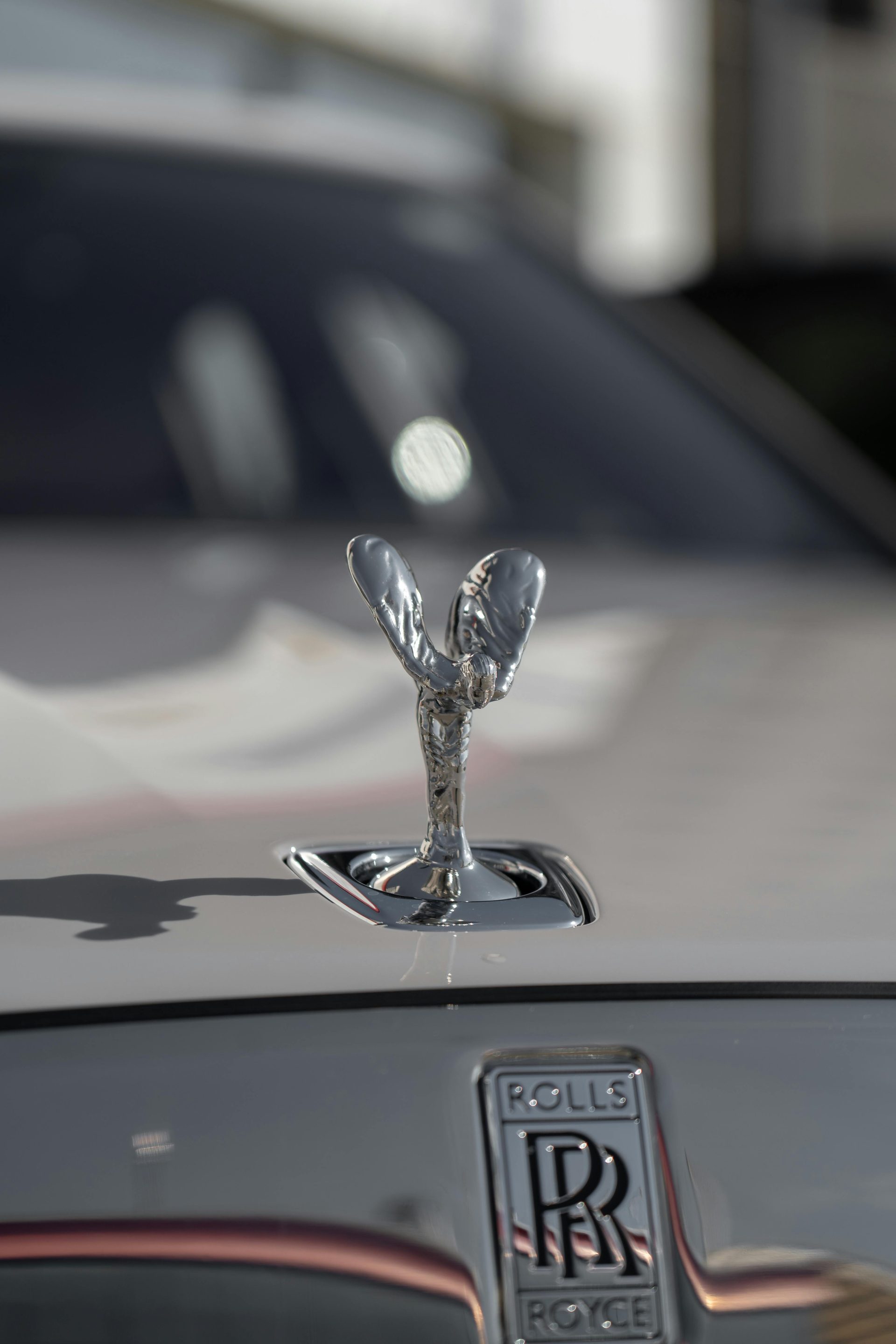 Nahaufnahme der ikonischen Kühlerfigur des Rolls-Royce Spirit of Ecstasy im hellen Sonnenlicht.